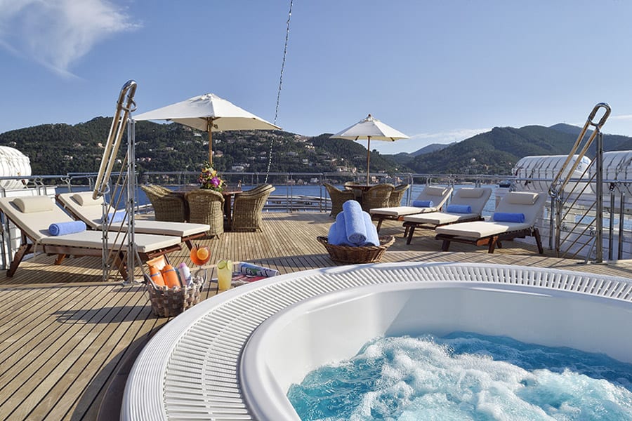 luxury experiences - yacht deck with whirlpool and sun beds with dining tables