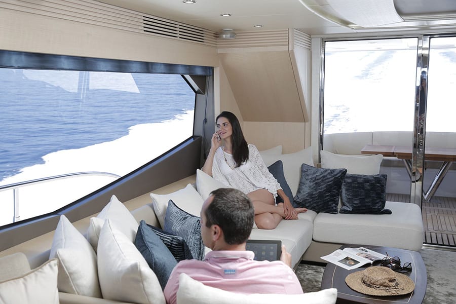 luxury yachts - woman and man relaxing on sofa in living room of yacht