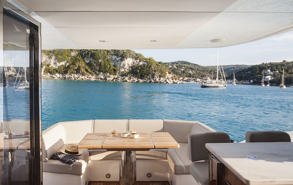 luxury yachts - covered deck of yacht with coast in background