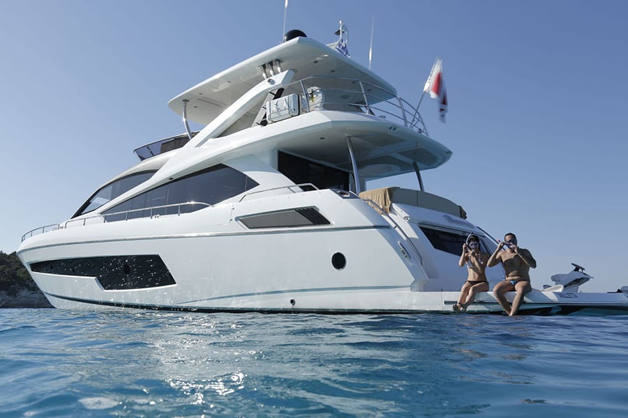 luxury yachts - couple with snorkeling gear seating on rear deck of yacht