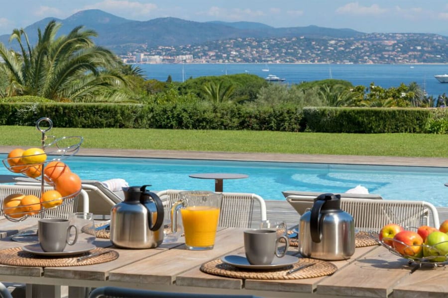 luxury villas - outside dining table with breakfast and pool with sea view