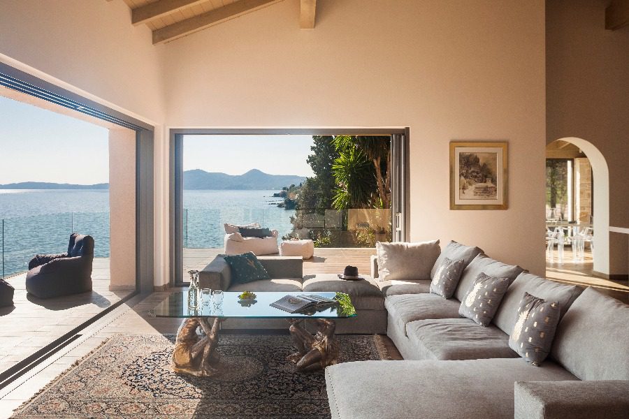 luxury villas - living room with large sofa and glass windows with beautiful sea view