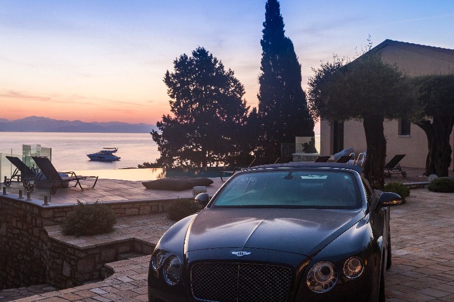 luxury villas - black sport car in front of villa with pool and sea view at sunset