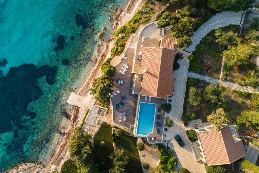 luxury villas - drone shot of villa with pool at the sea