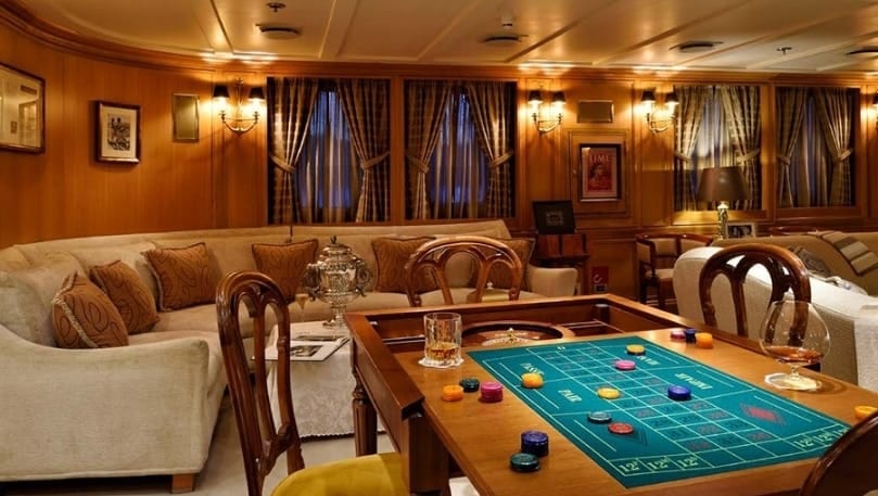 luxury yachts - inside of the yacht with gambling table and large sofa