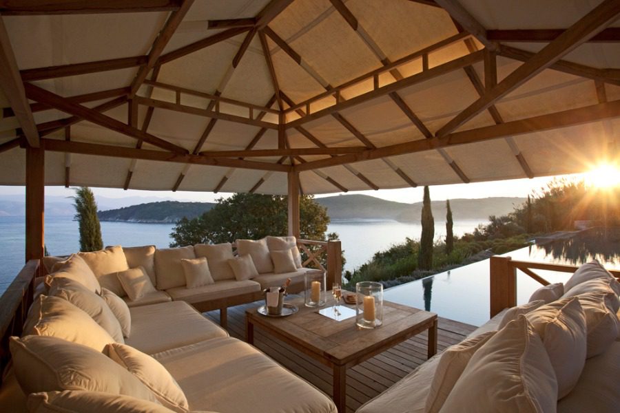 luxury villas - outside relaxing area with sofas and view to pool and the sea at sunset
