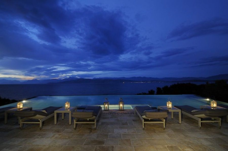 luxury villas - sun beds at the pool by night and cloudy sky
