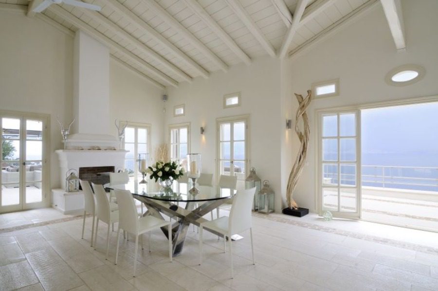 luxury villas - living room with dining table and fireplace with view to terrace and the sea