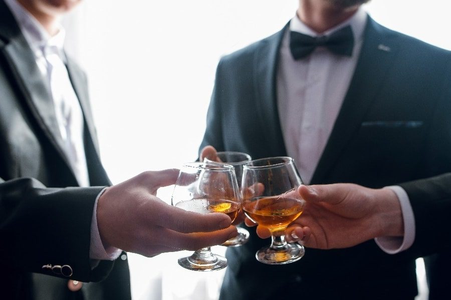 luxury experiences - man cheering with whiskey in suits