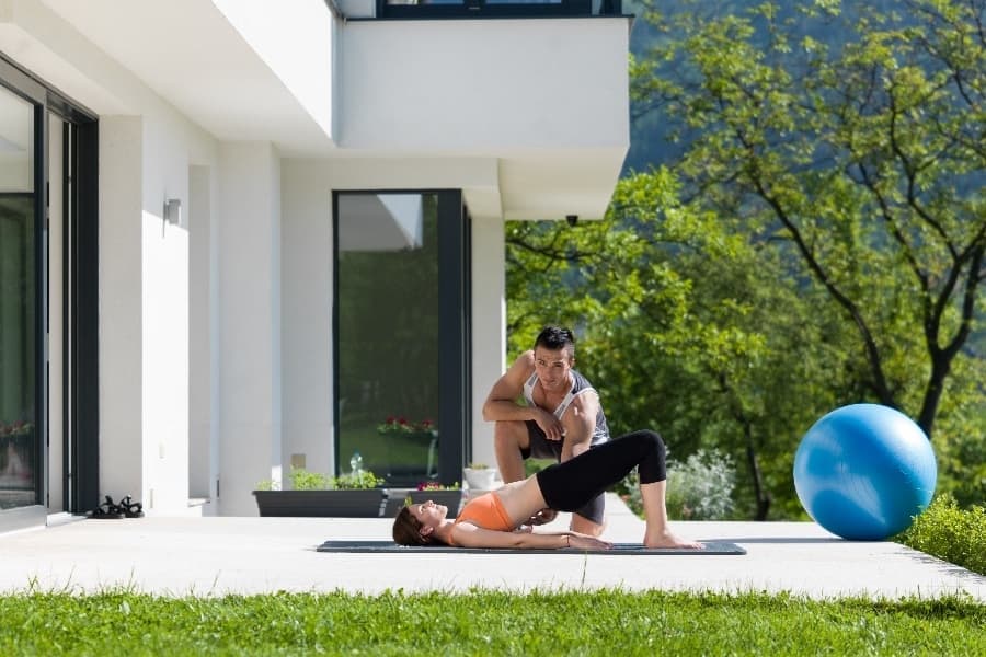 luxury services - man and women doing fitness outside on patio