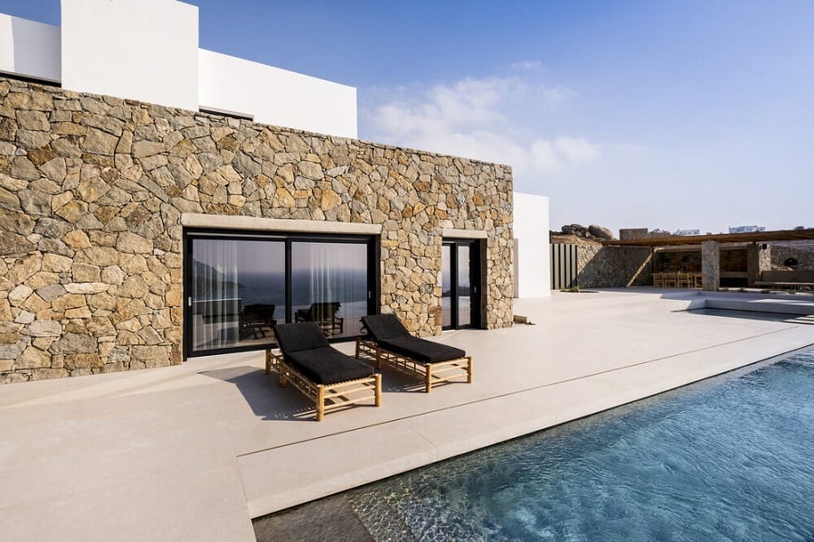 luxury villas - pool with sun beds and stone wall of villa