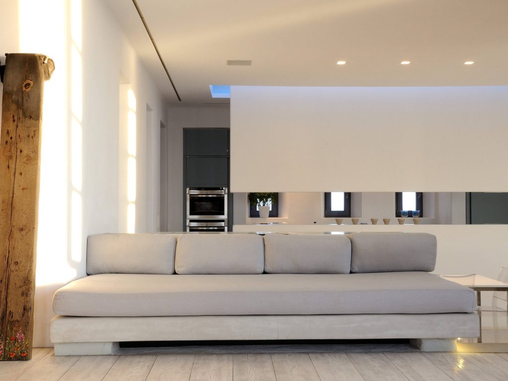 luxury villas - indoor living area with luxury grey couch and kitchen in the background